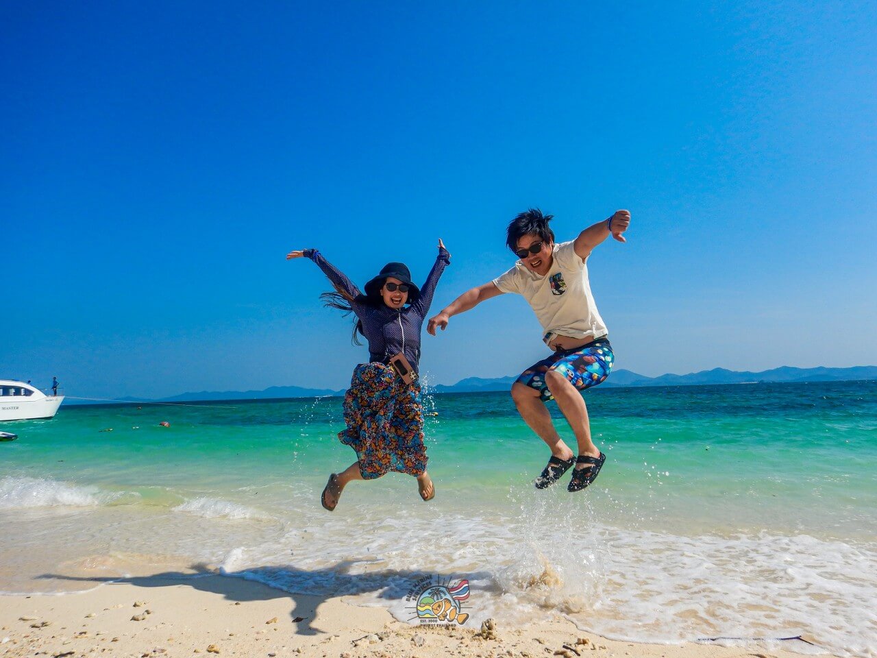 カイ島の白い砂浜でジャンプする2名のお客様
