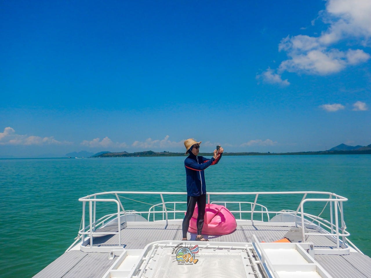 パンガー湾の船首で海を背景に撮影するお客様