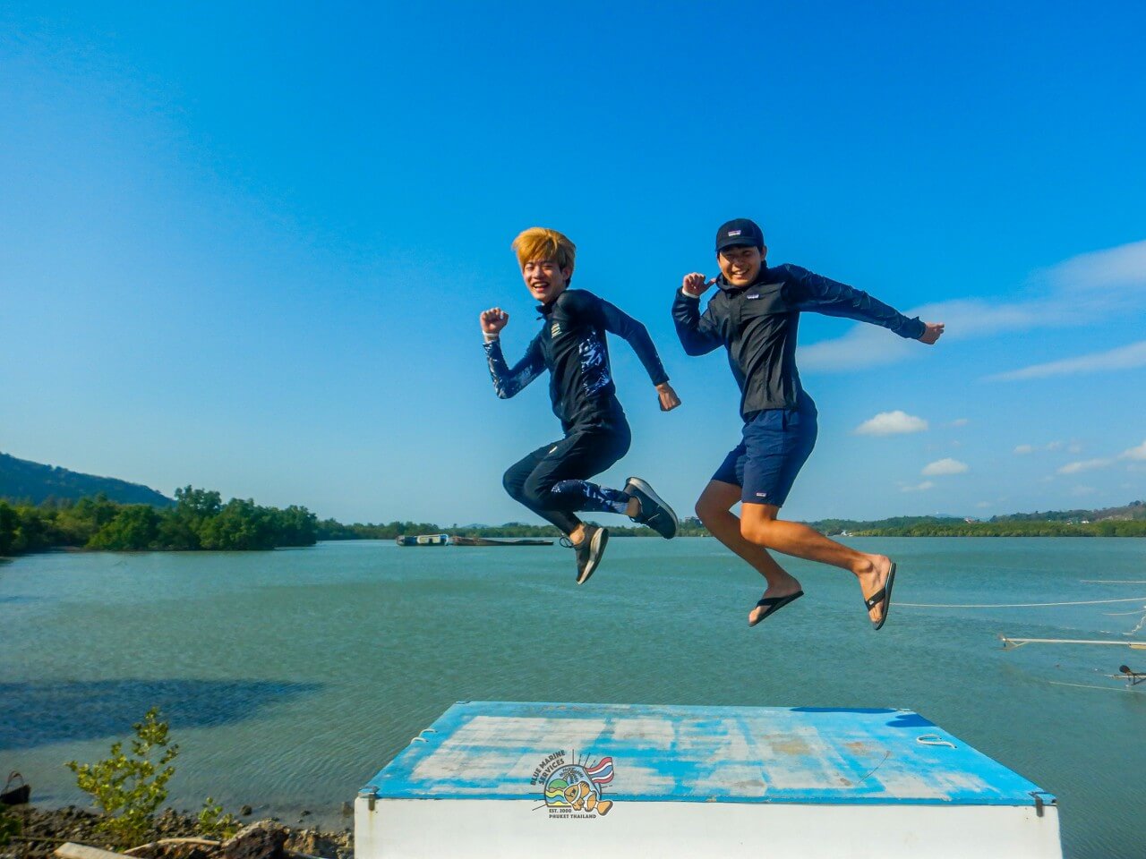 海を背景にジャンプ写真を撮る2名のお客様