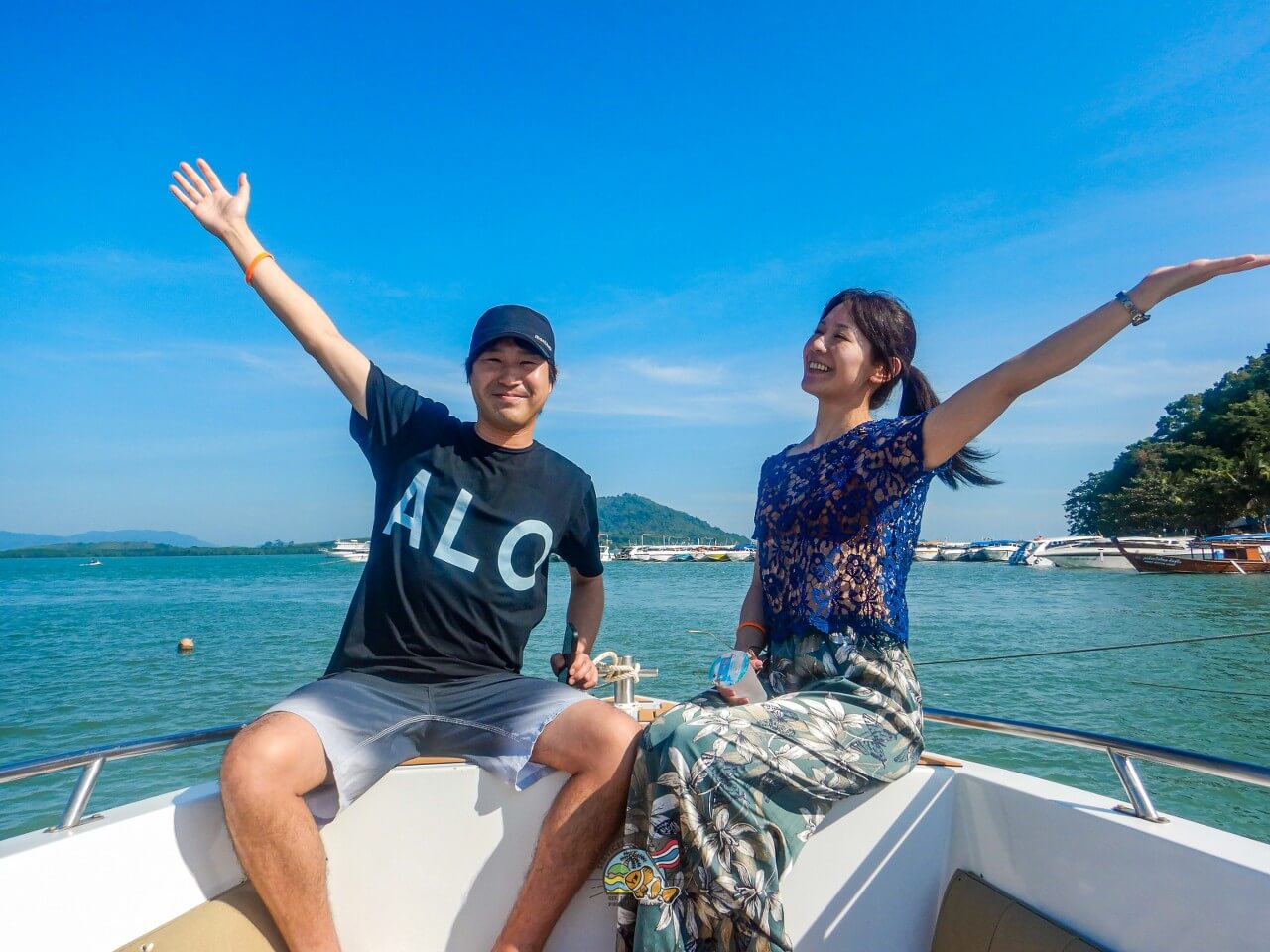 海を背景に船首で両手を広げる2名のお客様